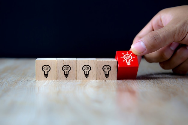 Close-up image of hand-picked cube shaped wooden toy blocks with light bulb symbol.