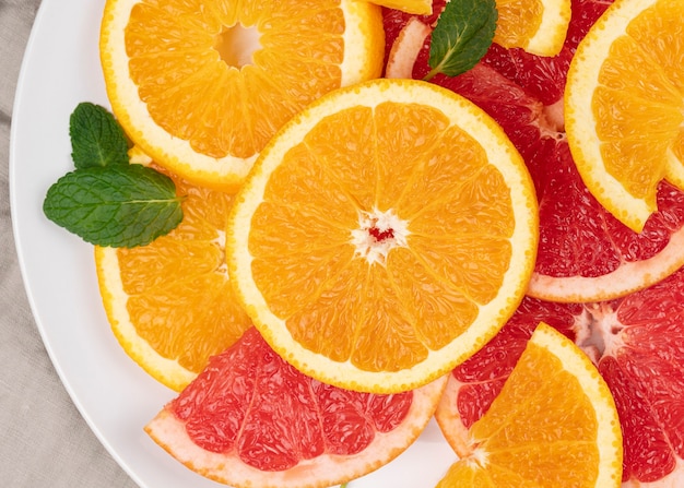 Close up image of juicy halved assorted citrus fruits, green leaves