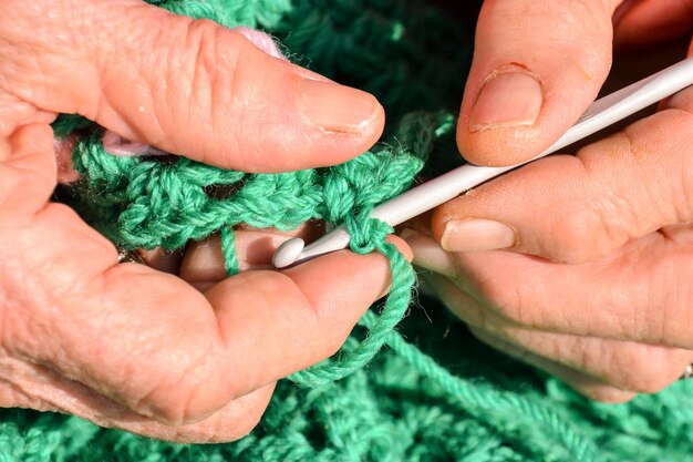 Close-up image of an old woman with knitting needles and wool