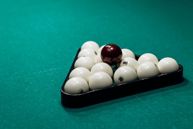 Close up image plastic rack triangle with white billiard balls on table with green surface