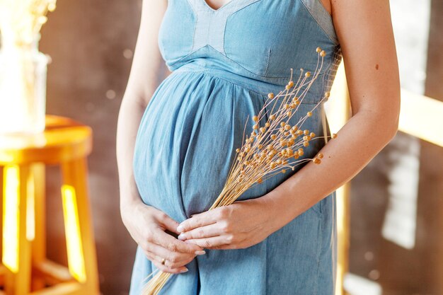 Immagine del primo piano della donna incinta che tocca la sua pancia con le mani.