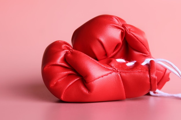 Photo close up image of red boxing gloves on pink background. sports concept