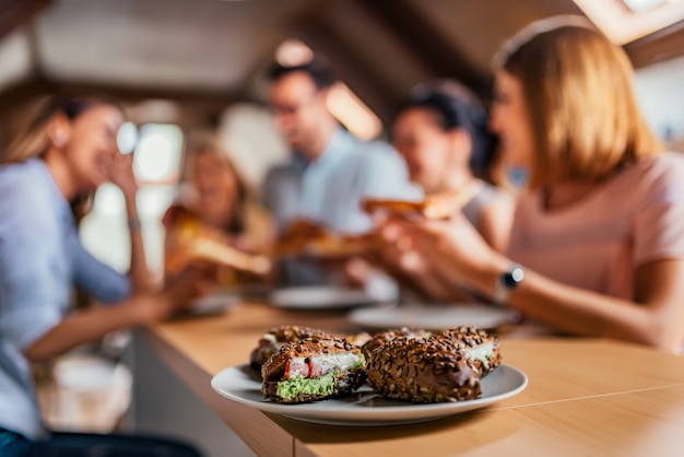 Close-up image of sandwich on a plate, blur business people 