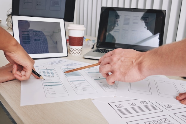 Immagine in primo piano dell'interfaccia utente e dei progettisti ux che puntano ai layout dell'interfaccia dell'applicazione mobile
