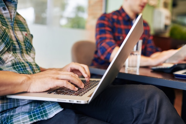 Foto immagine ravvicinata di studenti universitari che lavorano al computer portatile quando sono seduti al bar locale