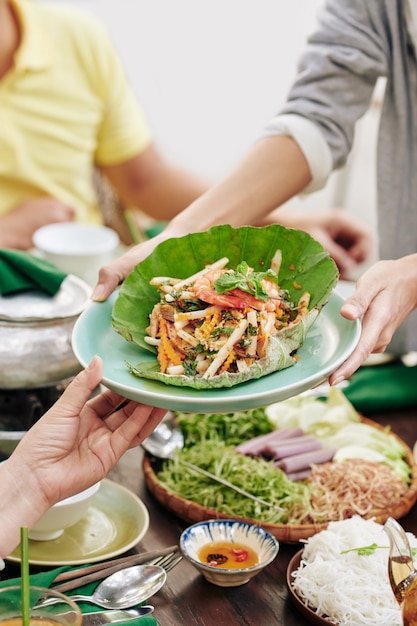 Close-up image of woman giving plate of decorated seafood salad to guests at family celebration