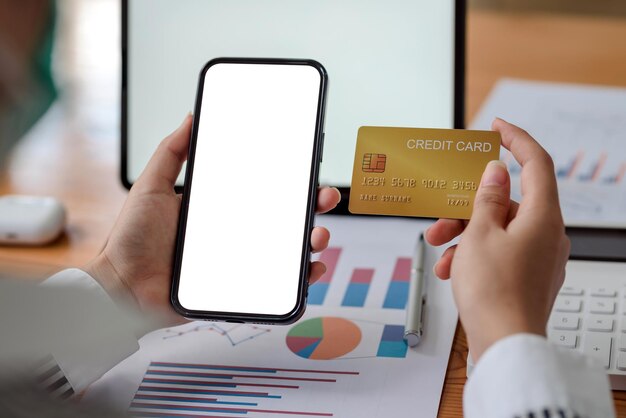 Close-up image of woman hands using smartphone blank white screen and holding credit card. Online shopping concept.