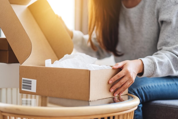 Immagine ravvicinata di una donna che riceve e apre una cassetta dei pacchi postali a casa per la consegna e il concetto di shopping online