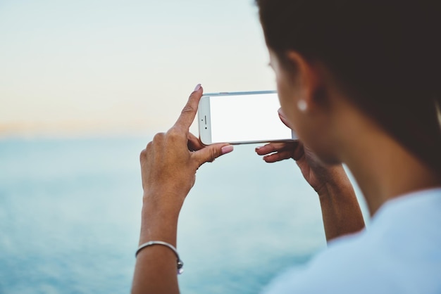 Close up image of woman's hands holding modern mobile phone with blank screen outdoors