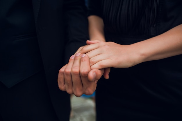 Close-up image of a young couple holding hands.