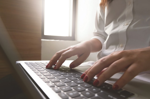 Close-up image of young woman hands typing and writing massages on laptop,working on cafe or home.