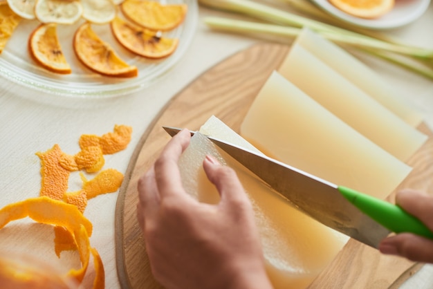 Close-up image of young woman making soap with thin orange and lemon slices