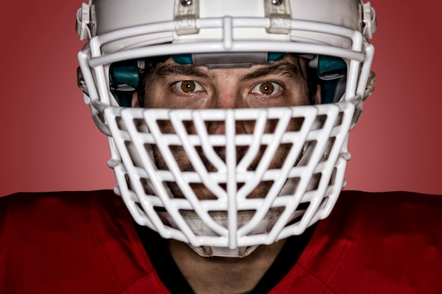 Close-up in de ogen van een voetballer met een rood uniform op een rode muur