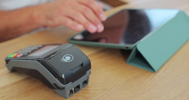 Close-up in het café maakt de man koffie voor een klant die met een contactloze mobiele telefoon betaalt aan het creditcardsysteem in café met digitale transactieservice