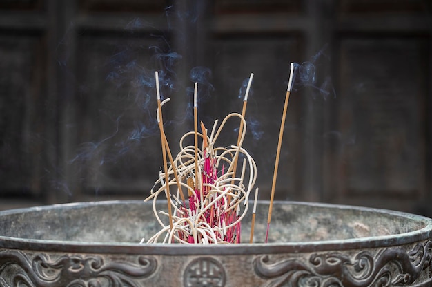 Close-up of incense sticks burning with smoke in buddhist temple of Hanoi city, Vietnam