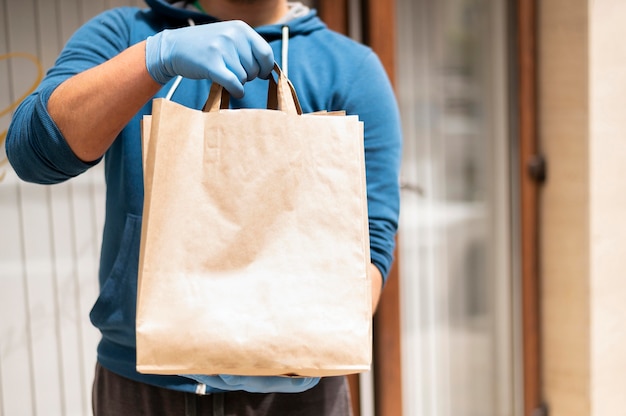 Close-up individual delivering shopping bag