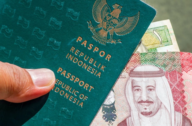 Primo piano del passaporto verde indonesiano e del riyal saudita, la valuta dell'arabia saudita, per la preparazione dei pellegrini dall'indonesia