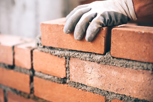 Photo close up of industrial bricklayer installing bricks on construction site