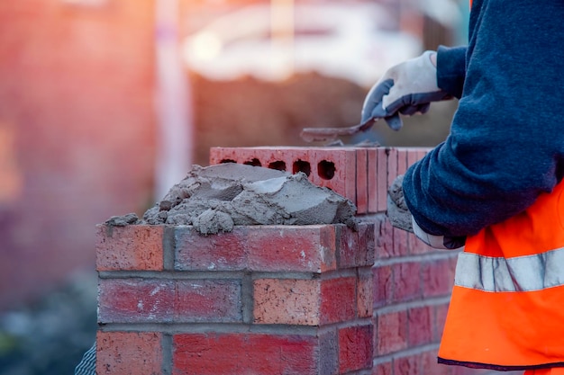 Close up of industrial bricklayer laying bricks on cement mix on construction site