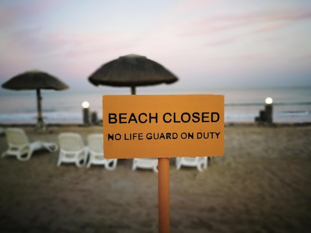 Photo close-up of information sign on beach against sky