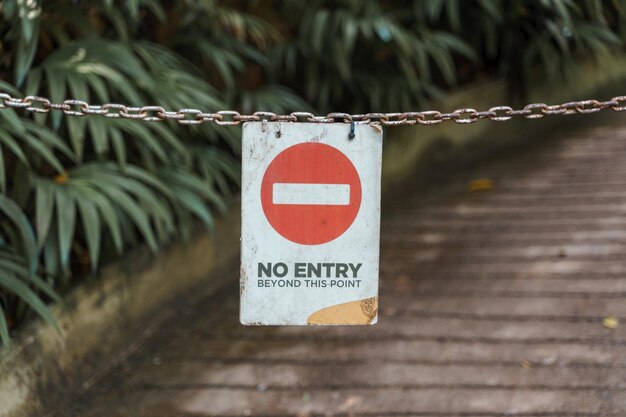 Close-up of information sign hanging on chain over footpath