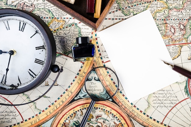 Close-up of ink bottle, clock and magnifying glass on map