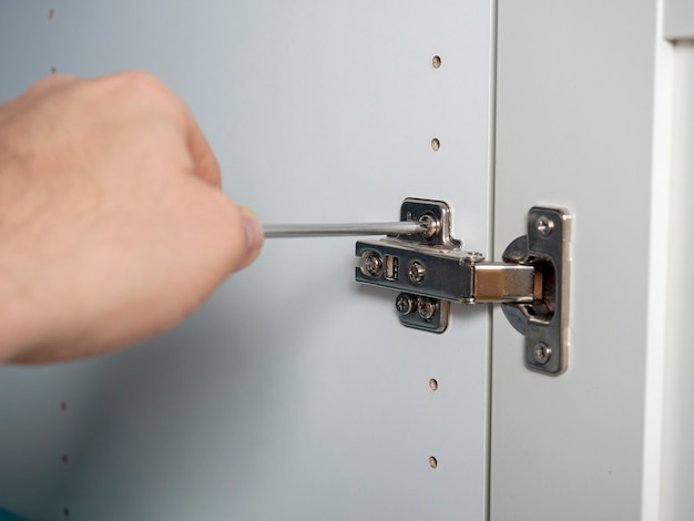 Photo close-up installation of furniture doors with a screwdriver, the concept of furniture assembly. selective focus