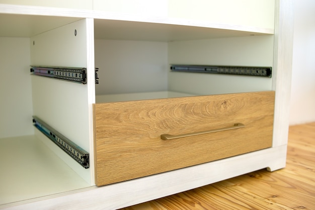 Close up of installation of wooden drawer in contemporary cupboard cabinet.