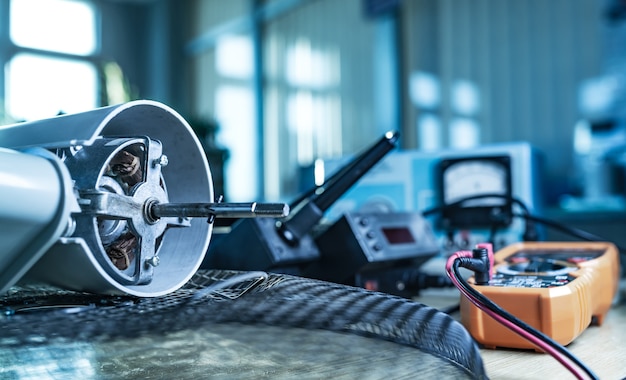 Close-up of an iron motor from home cooling fan and testind tools lies on a table in workshop. The concept of repair and restoration of damaged equipment