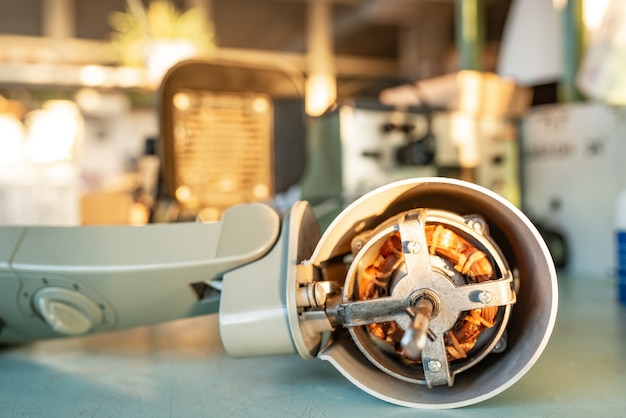 Close-up of an ironmotor from home cooling fan lies on a table during preventive cleaning, lubrication and repair in a specialized workshop. The concept of repair and restoration of damaged equipment