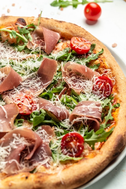 Primo piano di pizza al prosciutto italiano con rucola e parmigiano, immagine verticale. vista dall'alto.