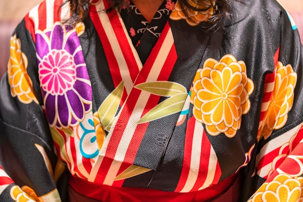 Foto close-up sul petto di una donna giapponese che indossa un kimono hakama in stile haikara con motivi di fiori