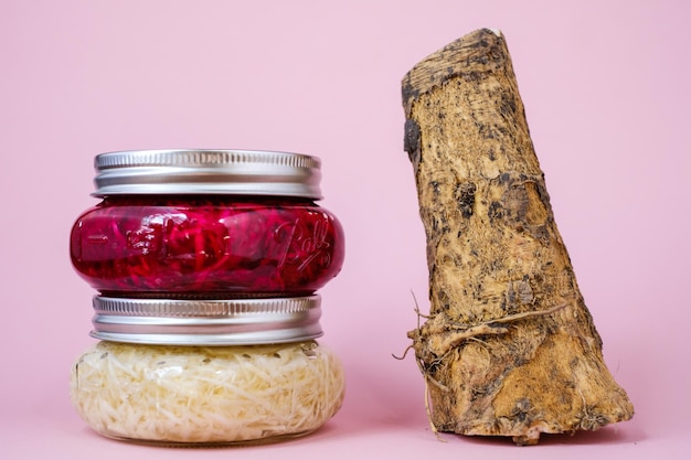 Close-up of jars with root against pink background