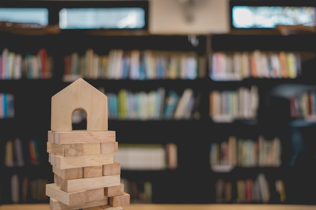 Photo close-up of jenga stack against bookshelf at library