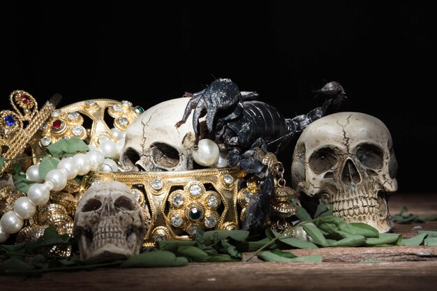 Photo close-up of jewelry and human skull on table against black background