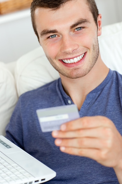 Close up of a jolly man holding a card and a laptop