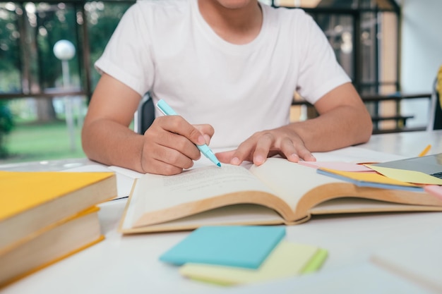 Close-up jonge Aziatische mannelijke student bereidt zich voor op het lezen van boeken voor examens aan de universiteit