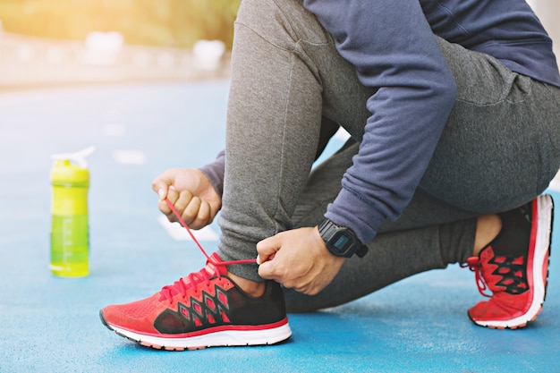 Close-up jonge man runner koppelverkoop schoenveters zitten op trappen, gezonde levensstijl en sport concepten.