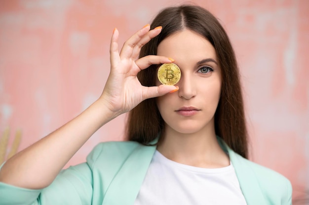 Close-up jonge vrouw houdt bitcoin voor ogen online virtueel toekomstig valutaconcept