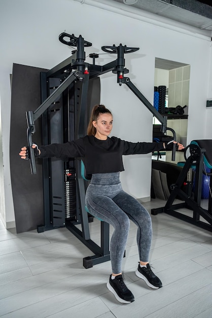 Foto close-up jonge vrouw traint spieren op oefenmachine in de sportschool