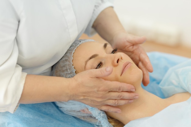 Close-up - jonge vrouwelijke klant van schoonheidssalon ligt op de bank in de spreekkamer tijdens therapeutische gezichtsmassage