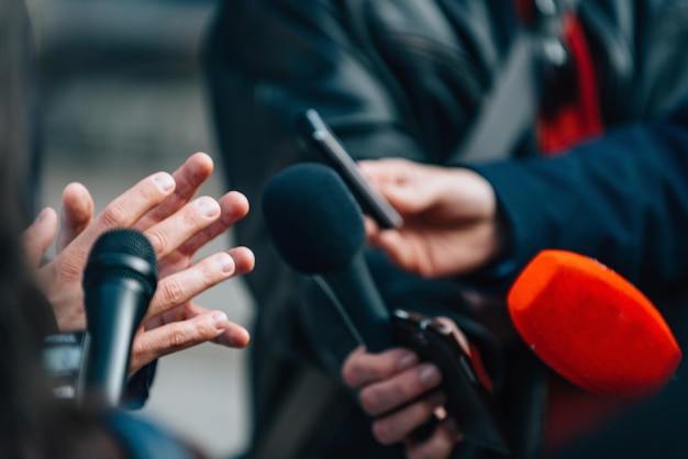 Photo close-up of journalists holding microphone while taking interview