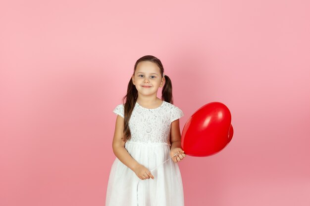 Close-up joyful girl in white dress holding red heart shaped balloon