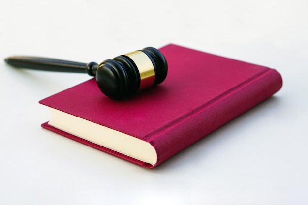 白い背景の上の法律の本に置かれた裁判官ガベル弁護士法の正義のクローズアップ