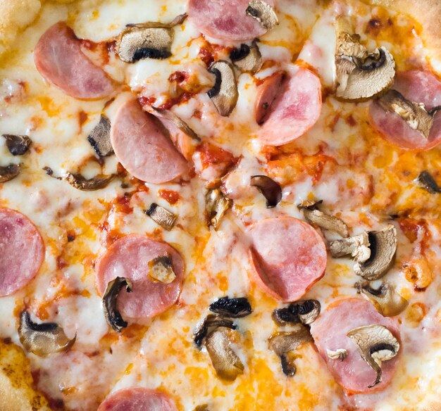 Close up of juicy pizza with ham mushrooms and cheese