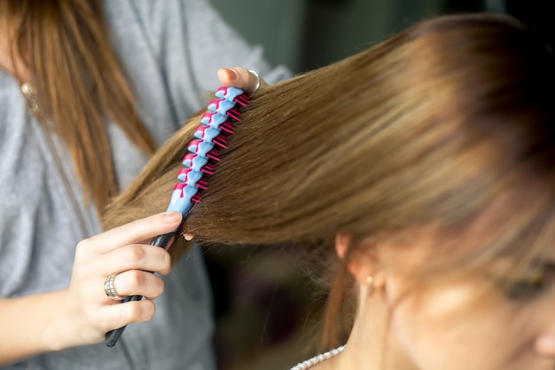 Foto close-up kapper coiffeur maakt kapsel.