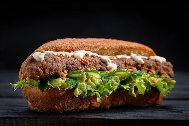 Закройте бутерброд кебаба на черной деревянной предпосылке. Концепция быстрого питания