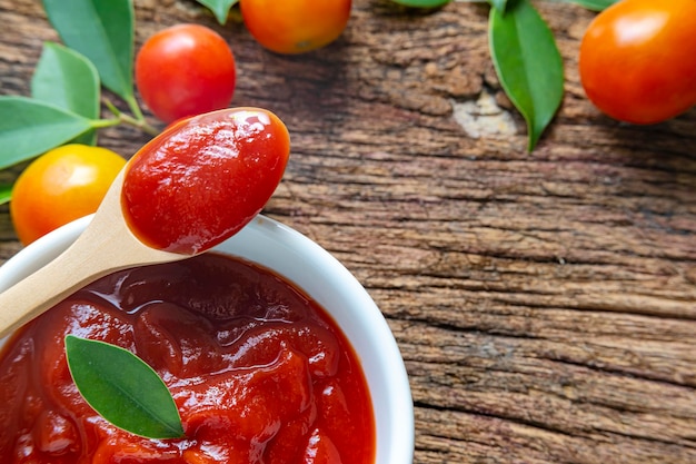 Close up of ketchup and tomatoes placed on a wooden background