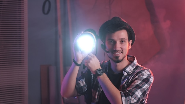 Close-up of key grip turning lamp to the camera and starting smiling.