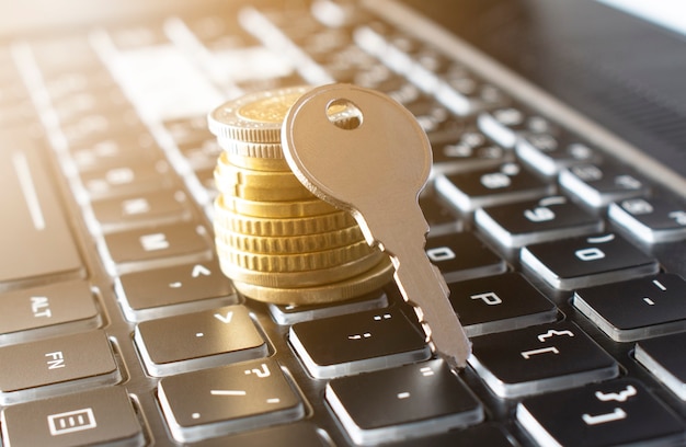 Close-up Of Key and stack of coins On black keyboard. Insurance concept